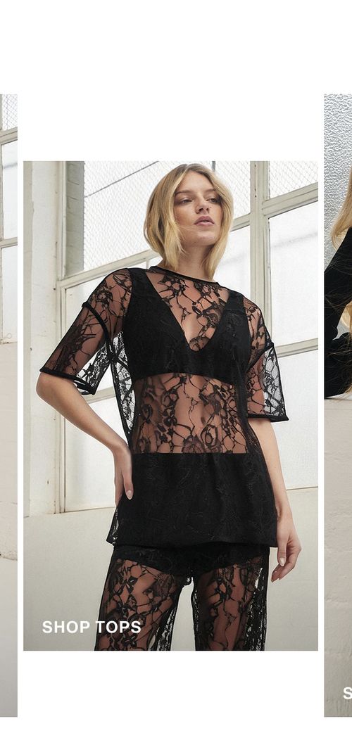 Model posing wearing a black lace top. SHOP TOPS.