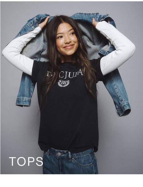 Young girl wearing a black Decjuba tee layered over a white long sleeve top. SHOP TEEN TOPS.
