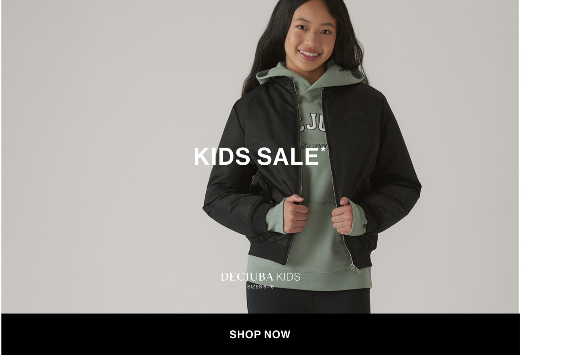 Model wearing a green hoodie and black bomber in a studio. Text reads KIDS SALE.