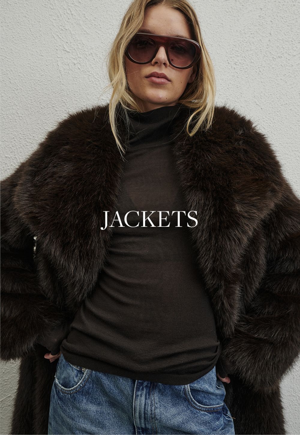 Model wearing a brown faux fur jacket. SHOP JACKETS.