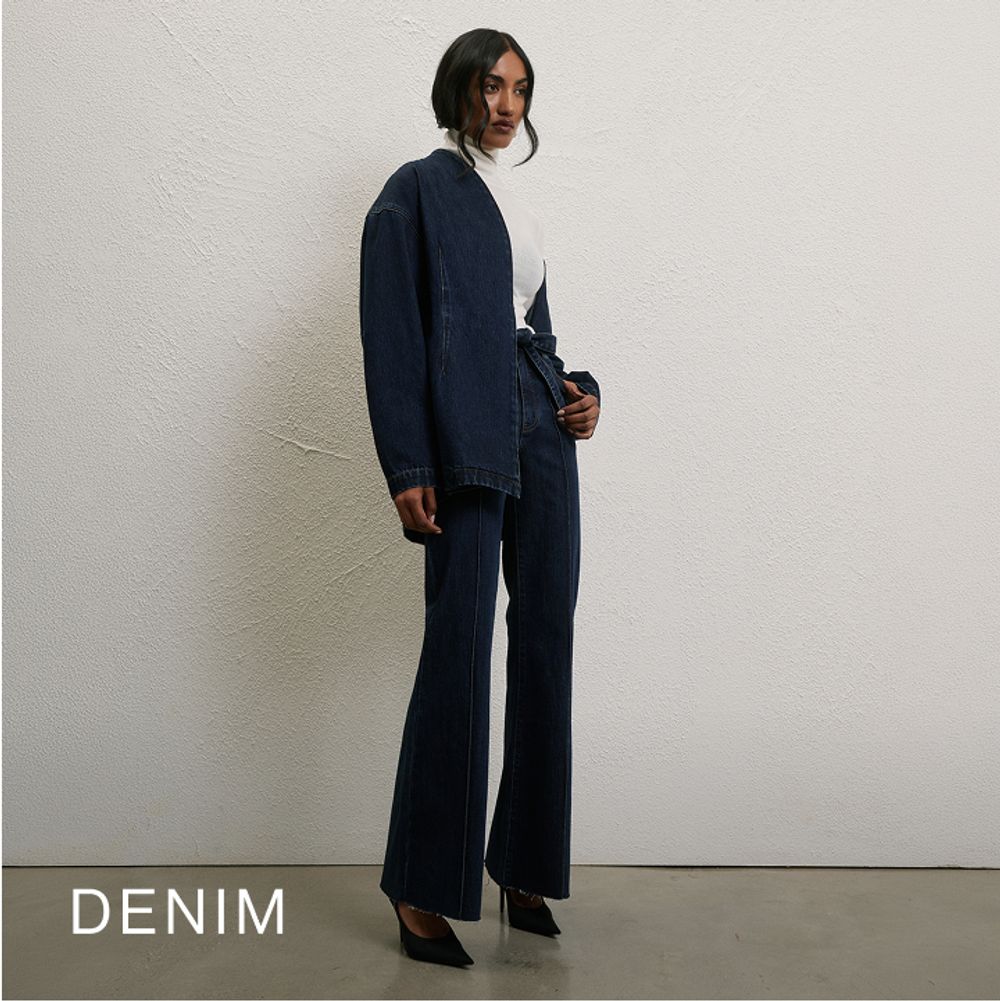 Model wearing a dark denim jacket and jeans. SHOP DENIM.