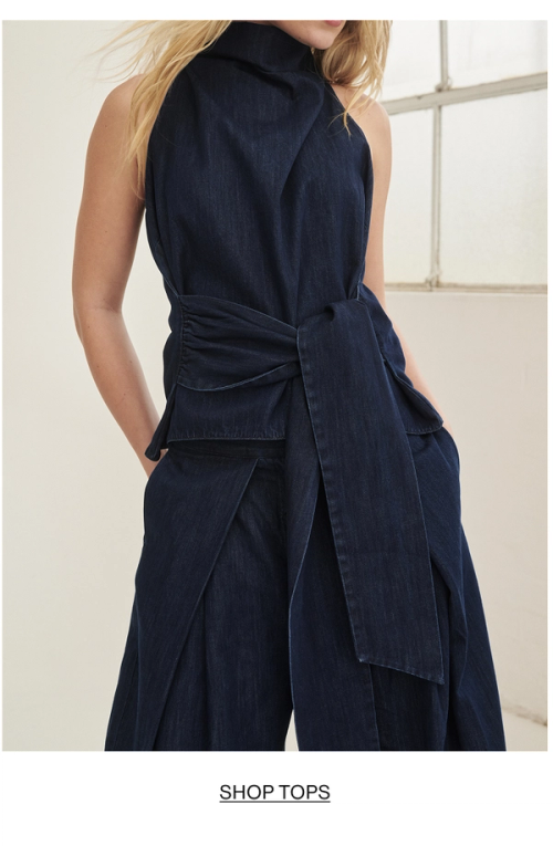 Model posing in a denim halter wrap top. SHOP TOPS