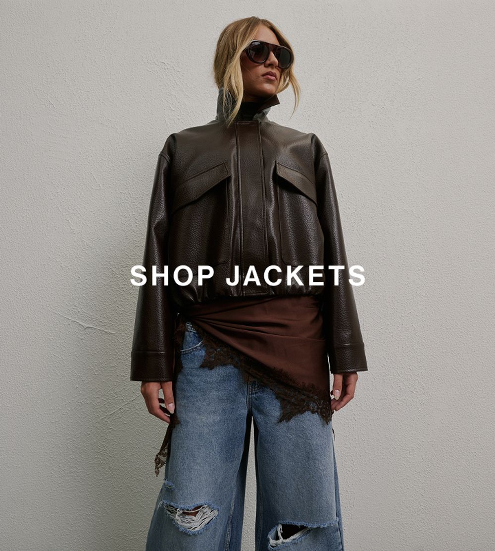 Model wearing a brown leather jacket layered over a top and jeans.