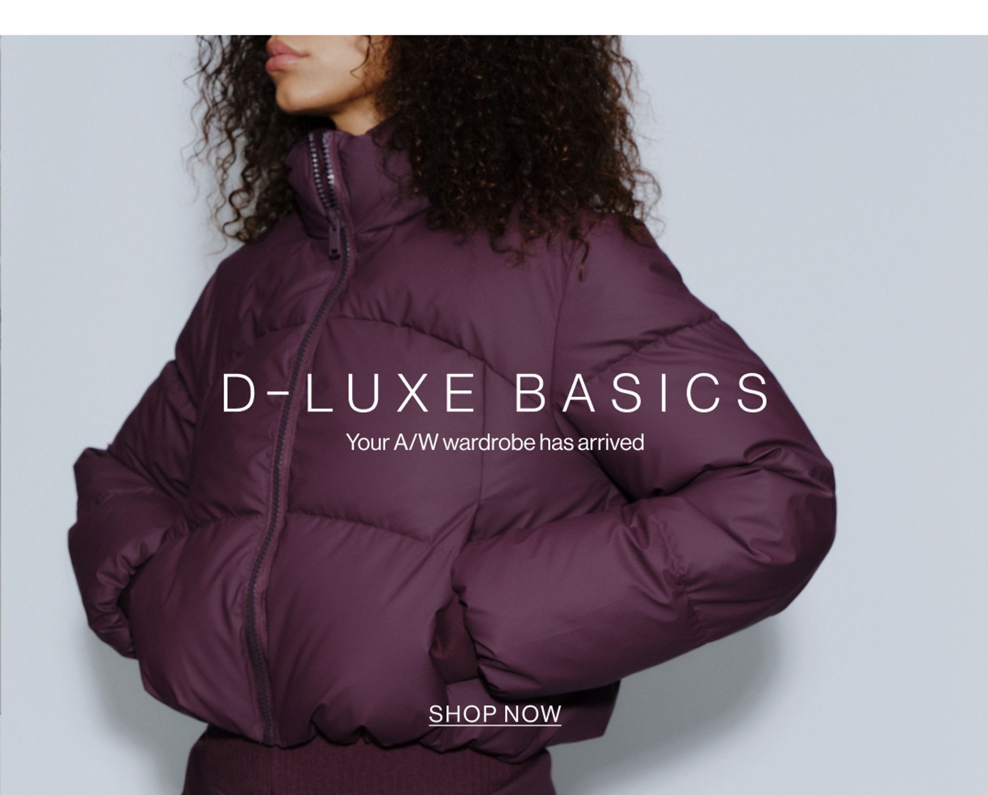 Model wearing a puffer jacket in midnight cherry in a studio. SHOP NEW D-LUXE.