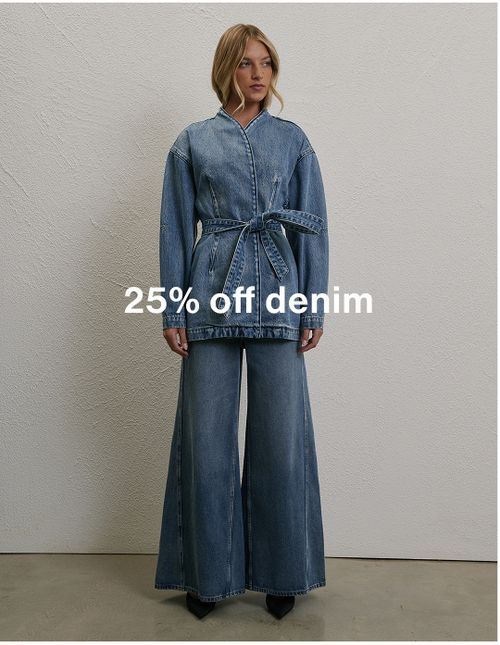 Woman posing in front of a white wall wearing a long sleeve denim set with text overlay which states "25% off denim"
