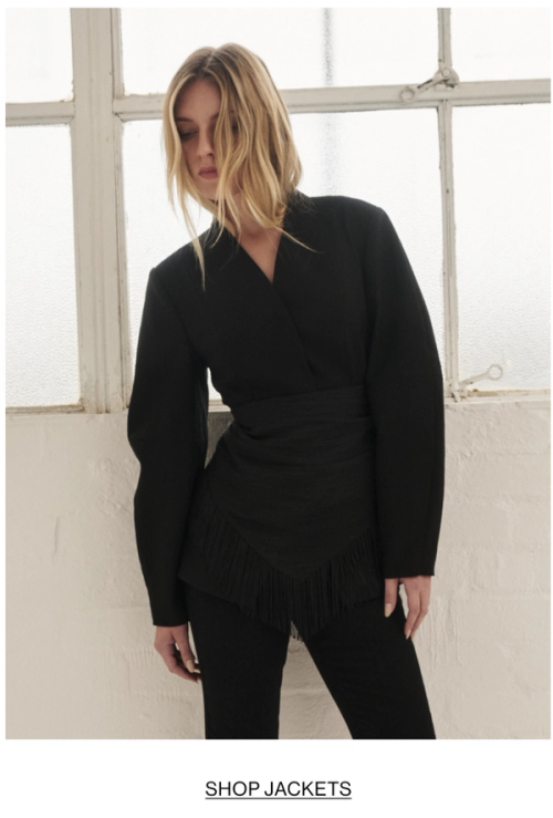 Woman posing is black barrel blazer with text that states shop jackets