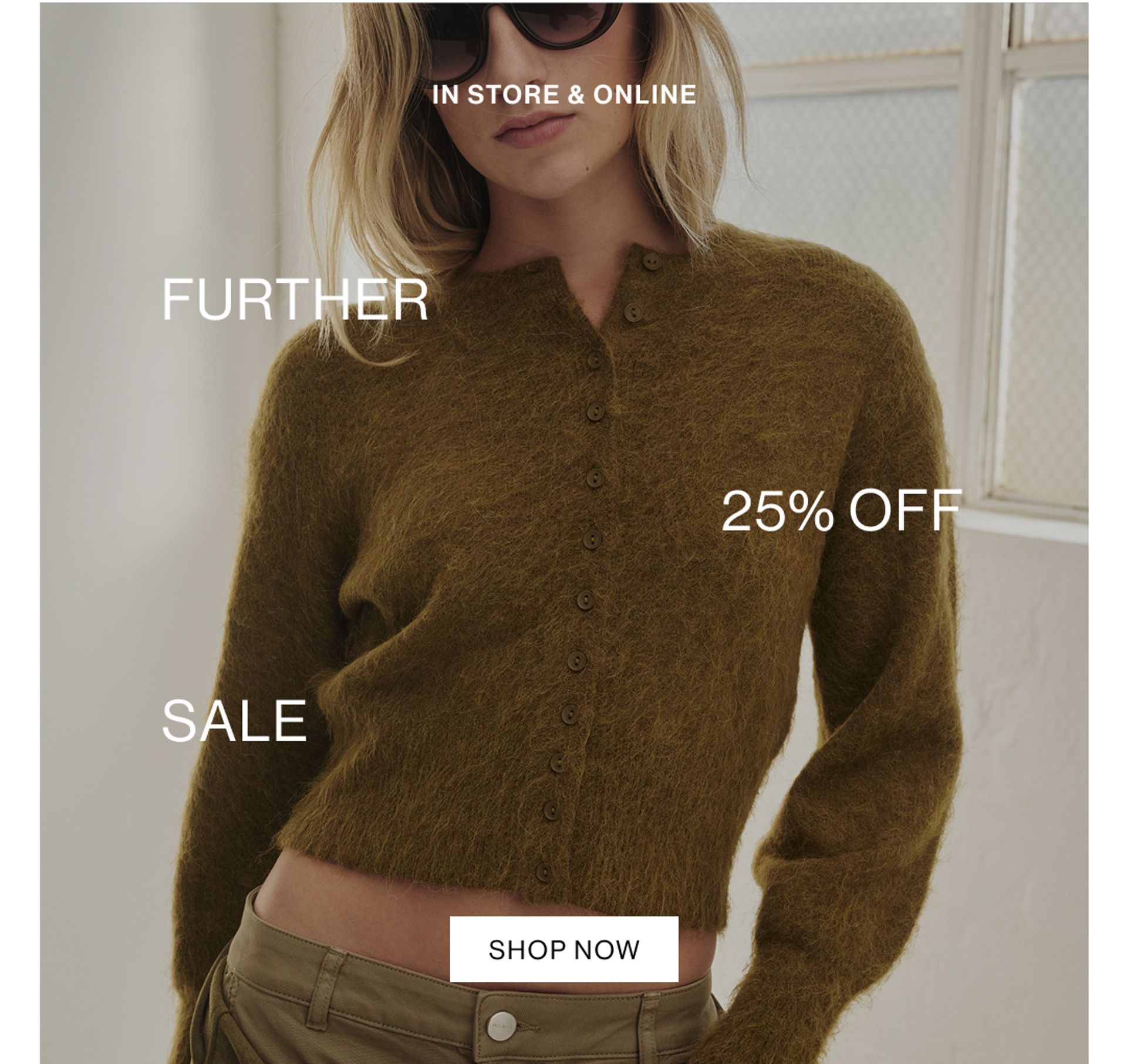 Model in a leather jacket standing in front of a white wall with text overlay which states "20% OFF DLUXE BASICS"