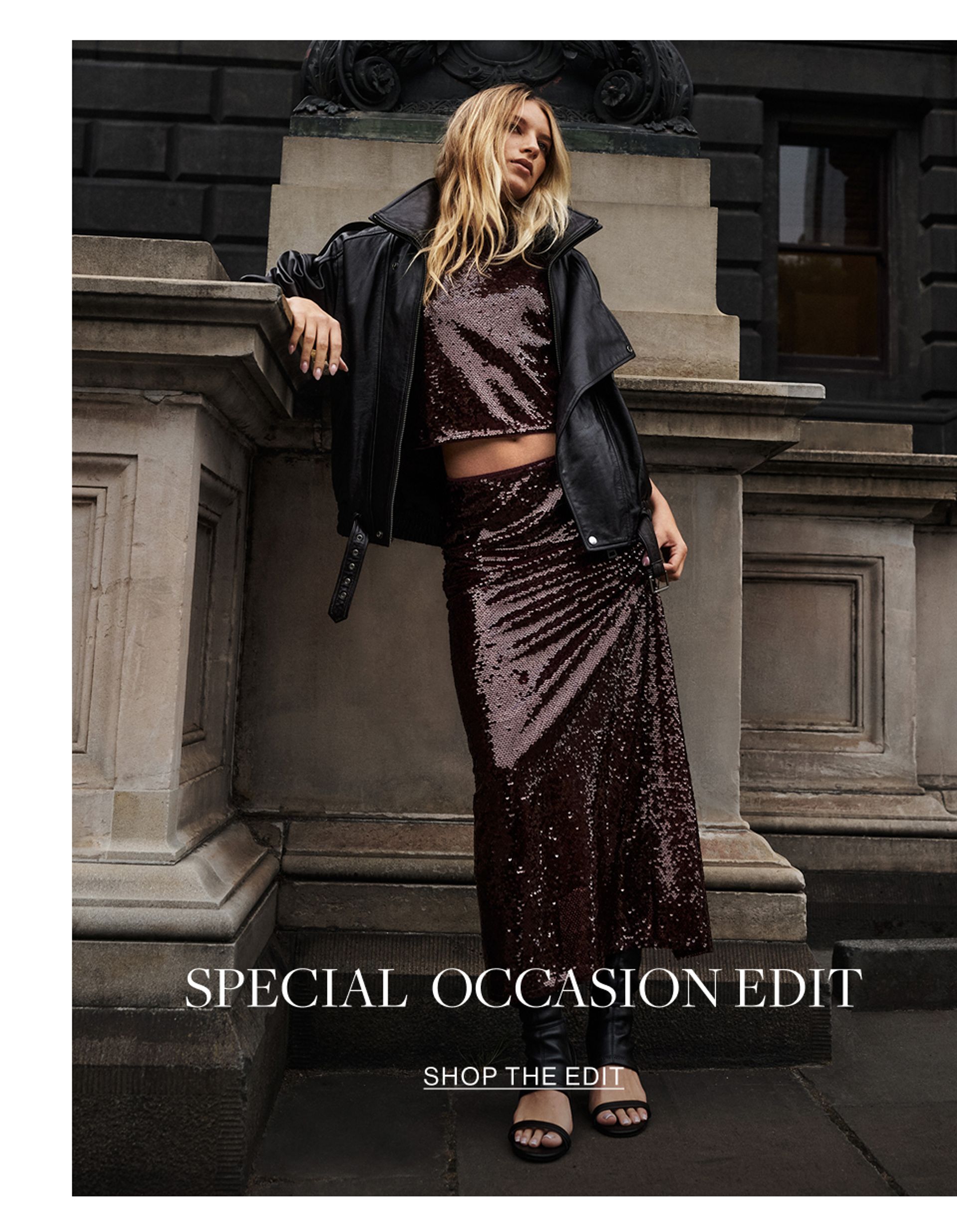 Woman walking across the road wearing a leather jacket and black skirt with text overlay that states "special occasion edit"