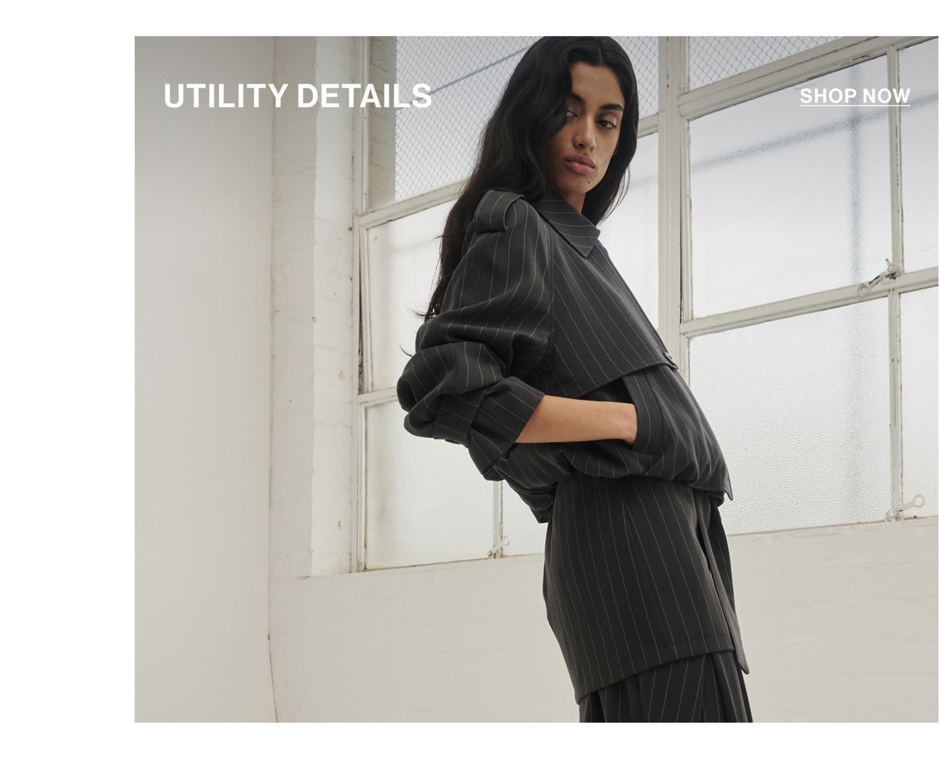 Model in a leather jacket standing in front of a white wall with text overlay which states "20% OFF DLUXE BASICS"