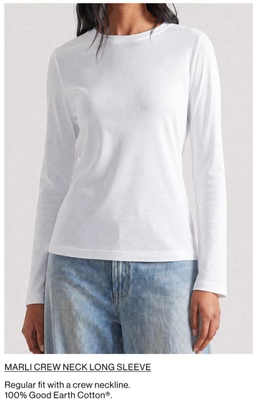 Woman standing in front of a white wall wearing a matching denim jacket and jeans set with texts that reads shop Amaya