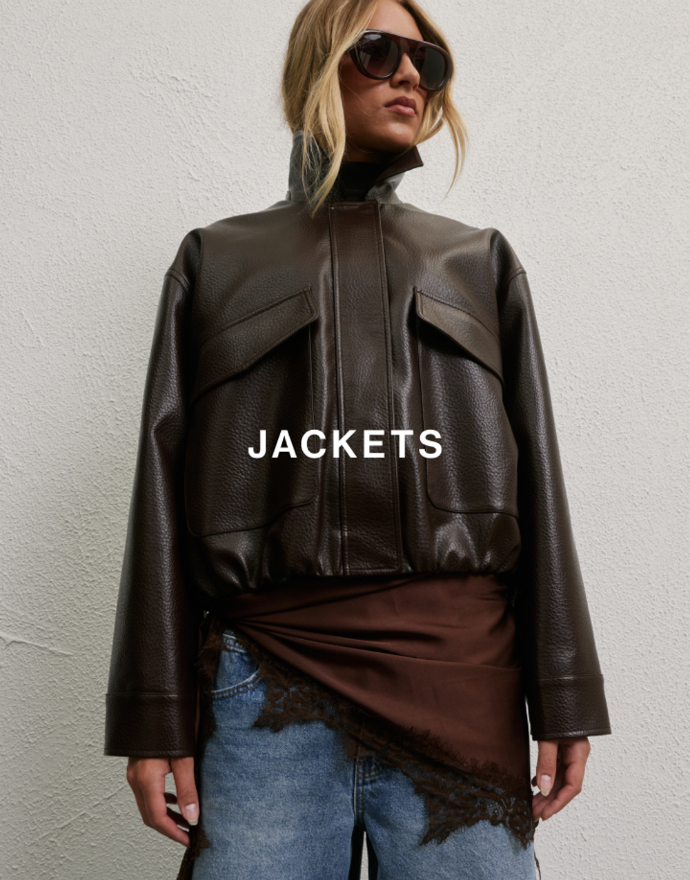 Model walking wearing a brown jacket which has text overlay jackets