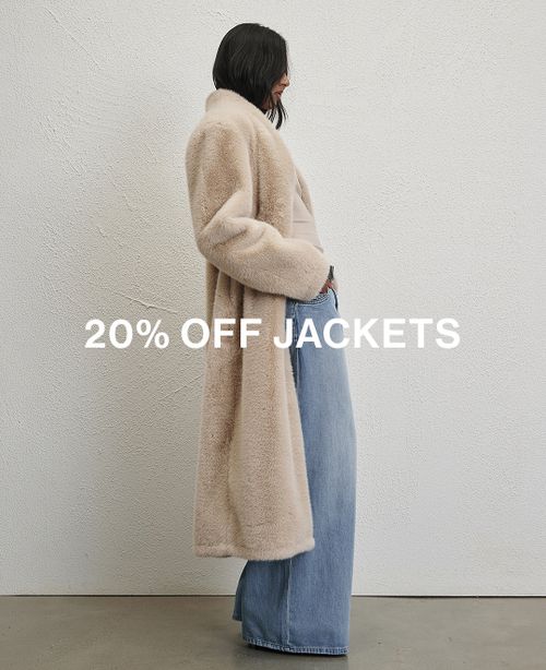 Woman sitting in front of a white wall wearing cream fur jacket with text overlay which states "20% off Jackets"