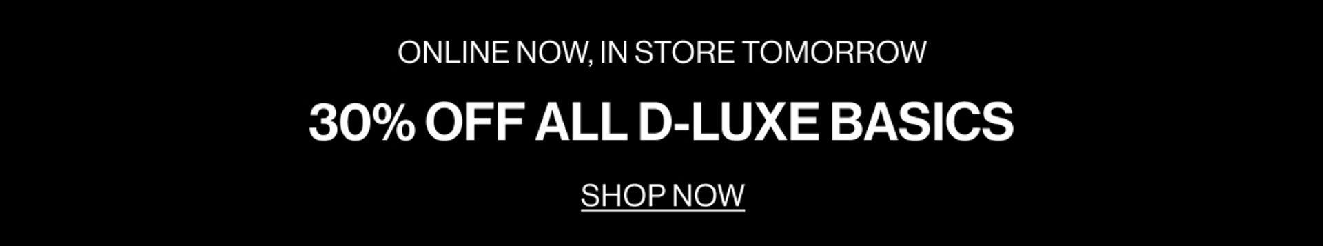 Model in a plum suit jacket standing in front of a white wall with text overlay which states "DLUXE BASICS"