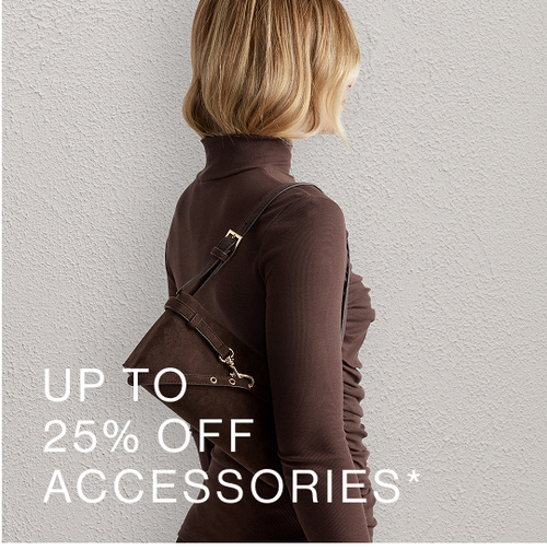 Woman posing in front of a white wall wearing a brown top, standing in front of a white wall with text overlay which states "Accessories"