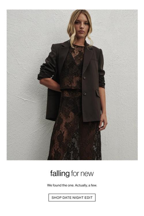 Woman standing in front of a white wall wearing a brown lace set and a blazer