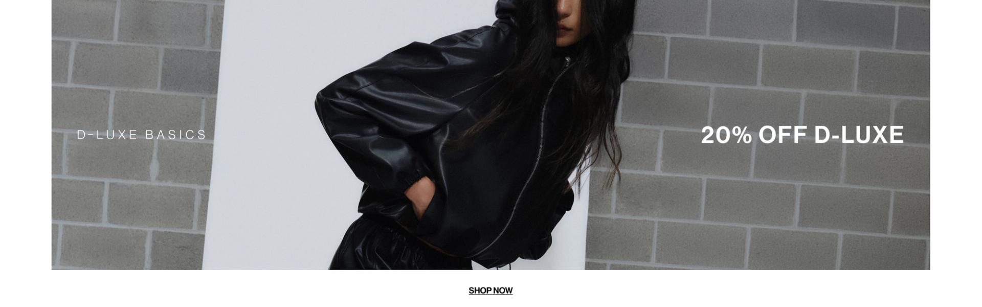 Model in a leather jacket standing in front of a white wall with text overlay which states "20% OFF DLUXE BASICS"