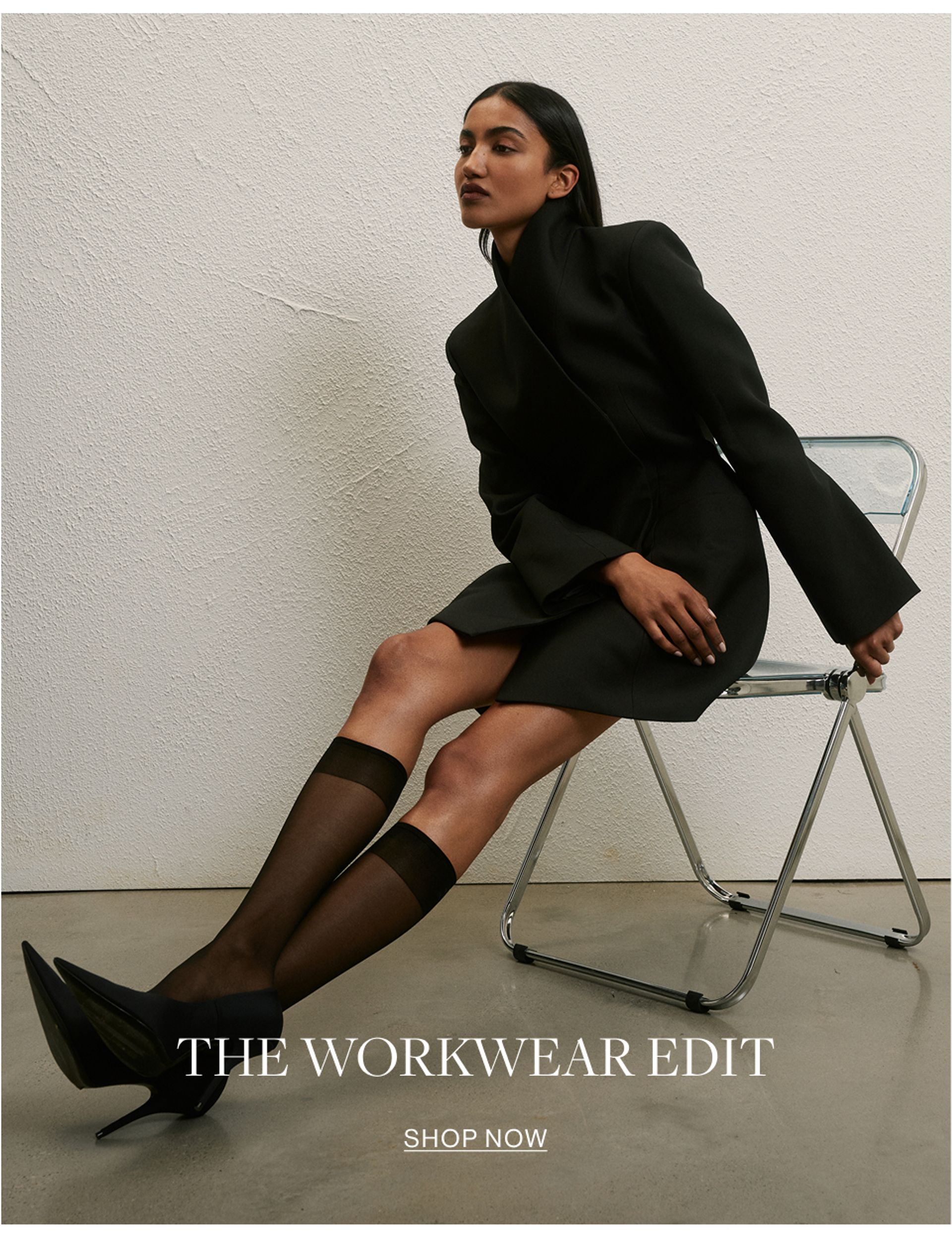 Woman sitting in a modern chair wear and black collared dress with text overlay that states "The workwear edit"