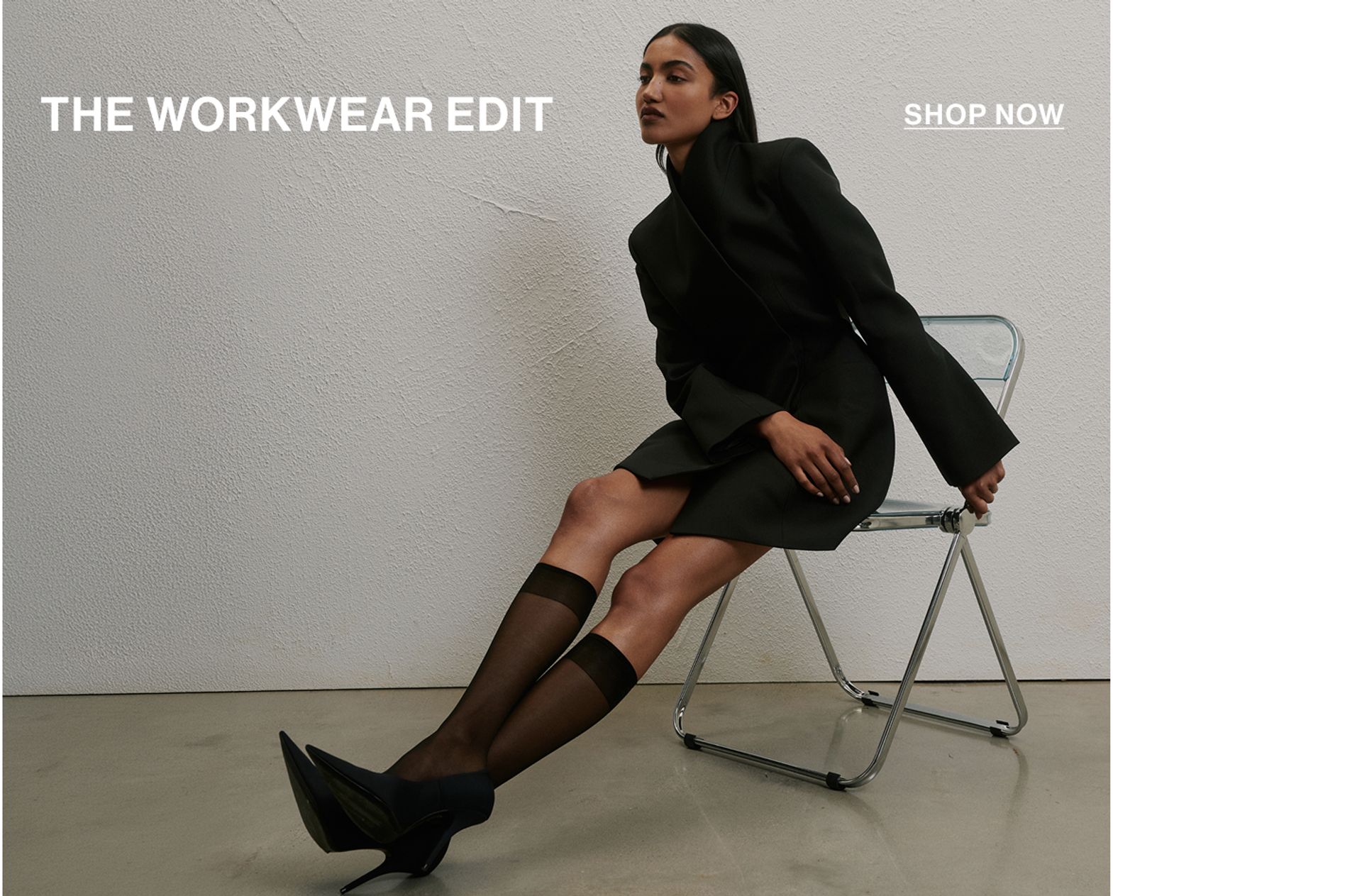 Model in a leather jacket standing in front of a white wall with text overlay which states "20% OFF DLUXE BASICS"
