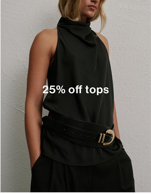 Woman wearing a black turtle neck top standing in front of a white wall with text that states 25% off tops