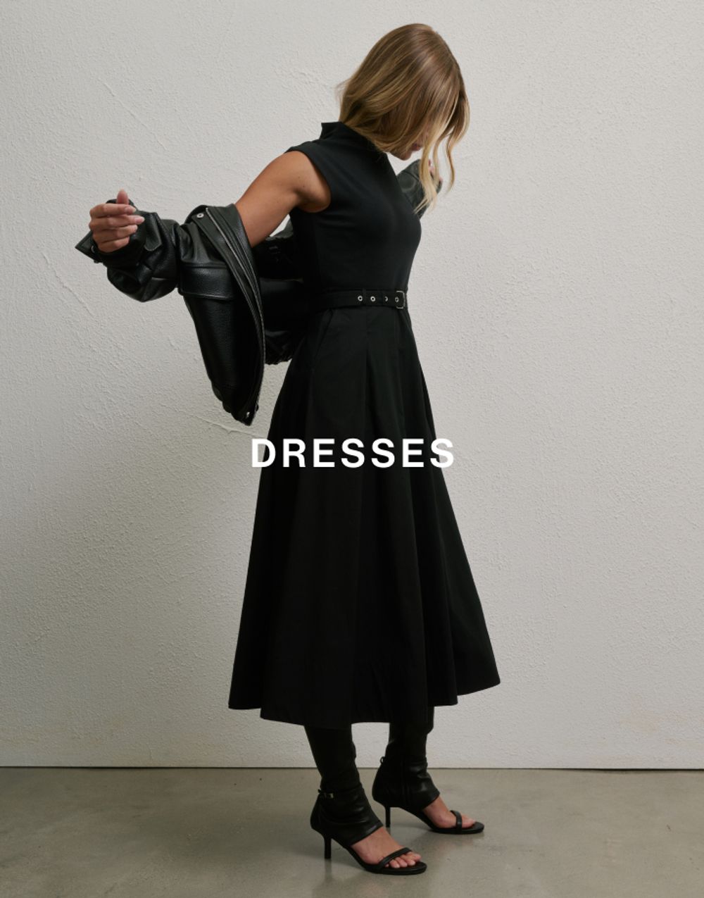 Woman putting a black jacket on in a black dress with text overlay which states dresses