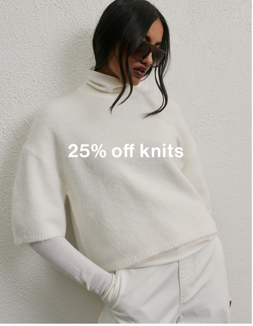 Woman posing in front of a white wall wearing a white top and pants with text overlay which states "25%off knits"