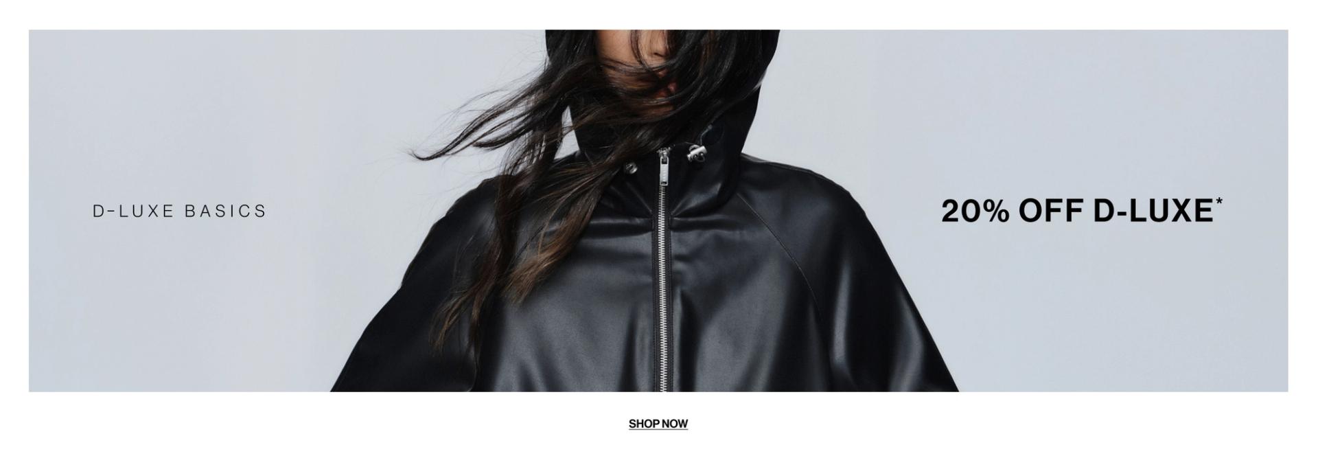 Model in a leather jacket standing in front of a white wall with text overlay which states "20% OFF DLUXE BASICS"