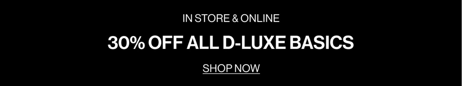 Model in a plum suit jacket standing in front of a white wall with text overlay which states "DLUXE BASICS"
