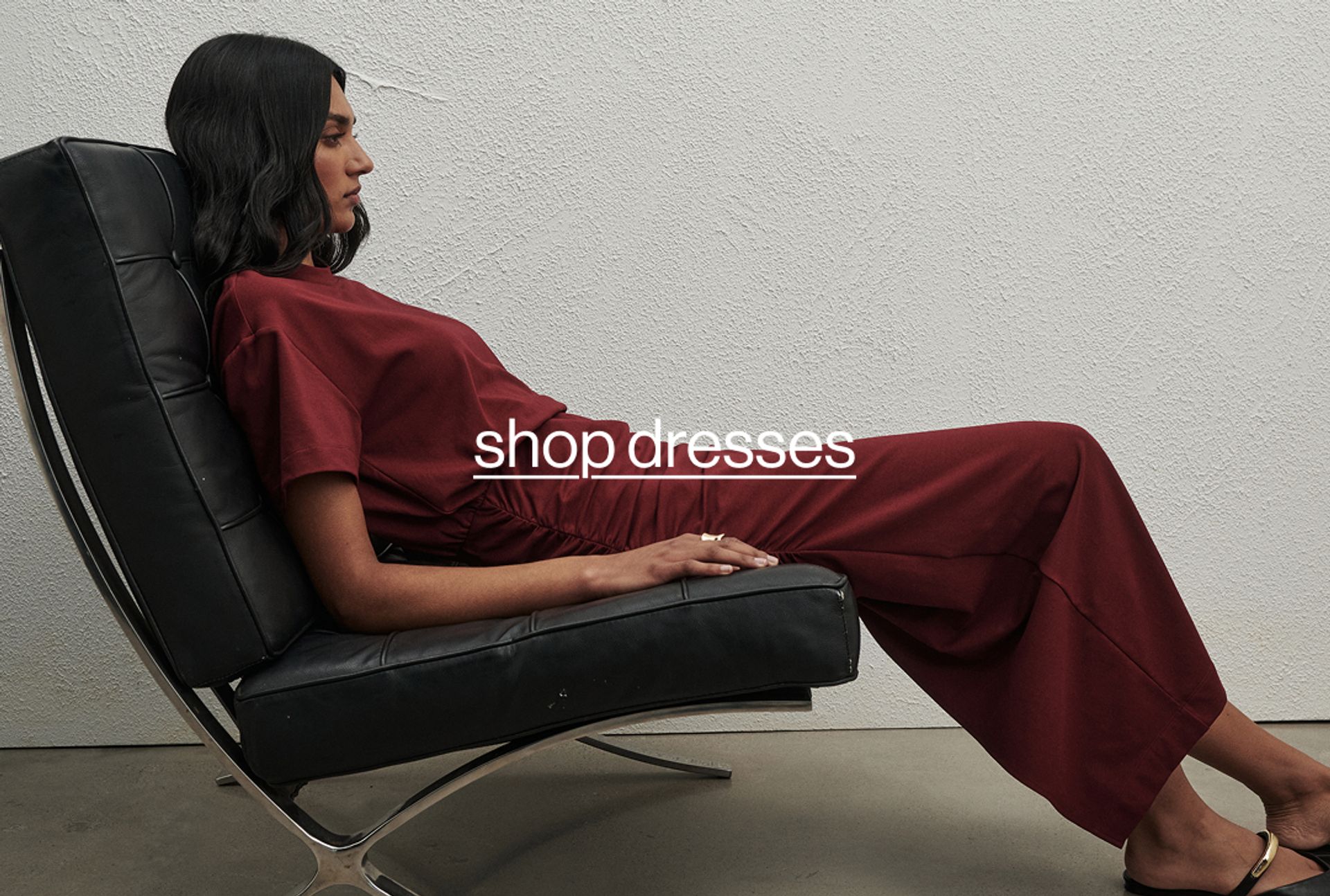 Woman sitting on a black couch wearing a red dress with text that reads "shop dresses" 