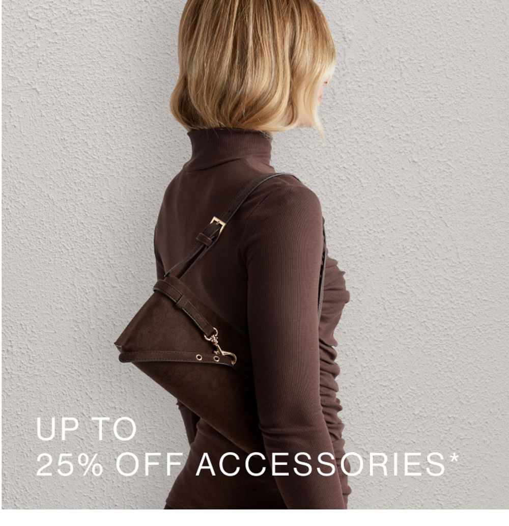 Woman posing in front of a white wall wearing a brown top, standing in front of a white wall with text overlay which states "Accessories"