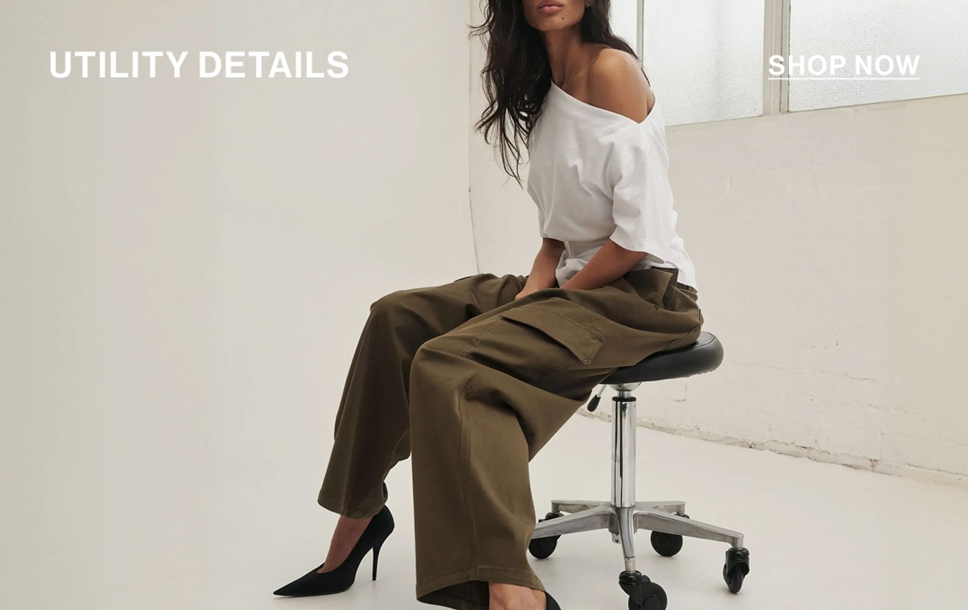 Model in a leather jacket standing in front of a white wall with text overlay which states "20% OFF DLUXE BASICS"