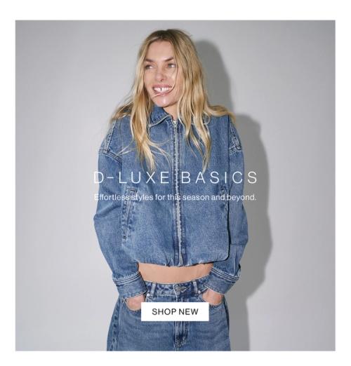 Model in a denim jacket and jeans posing with her hands in her pocket against a white wall with one hand in her pocket. Text reads ‘DLUXE basics: the latest essentials for this season and beyond.'