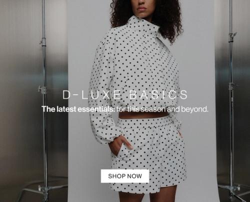 Model in a polka dot coordinated set, standing casually against a metal wall with one hand in her pocket. Text reads ‘DLUXE basics: the latest essentials for this season and beyond