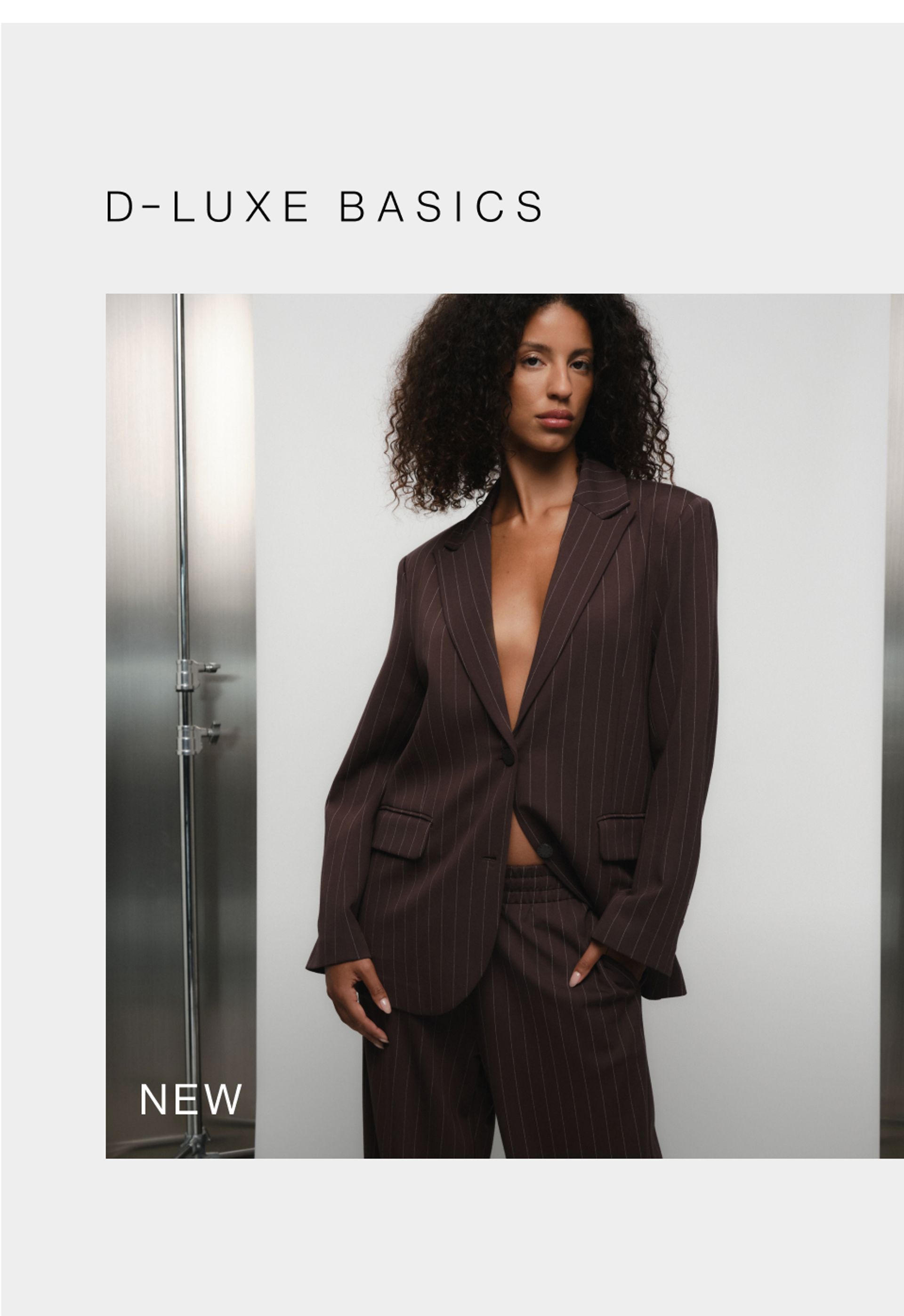 Model in a brown jacket standing in front of a white wall with text overlay which states new