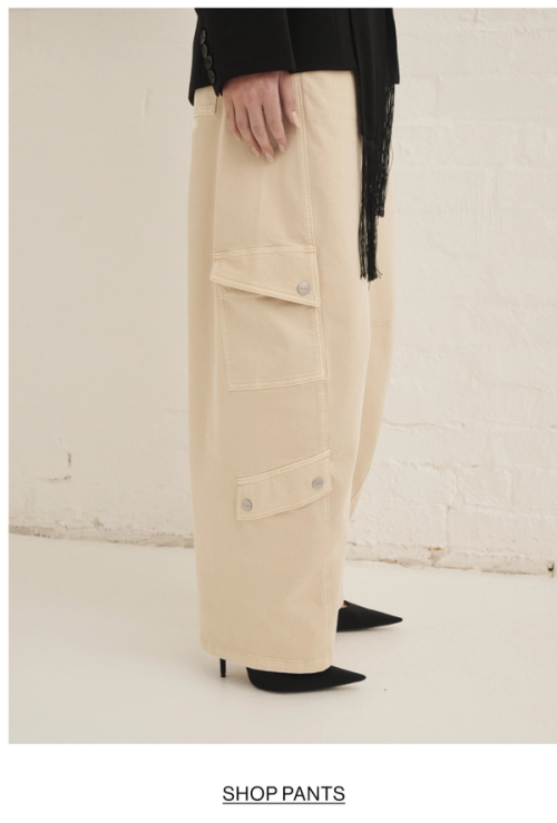 Woman posing in almond colour pants with text overlay shop pants