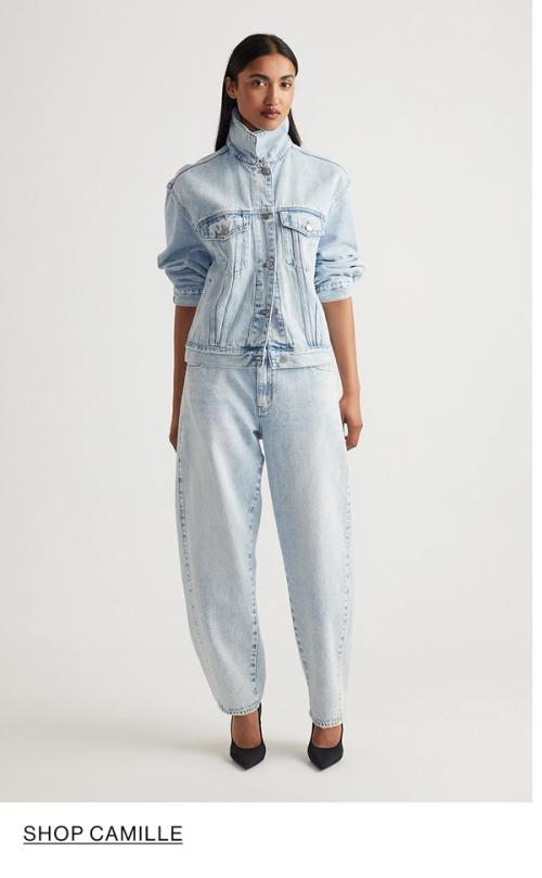 Woman standing in front of a white wall wearing a matching denim jacket and jeans set with texts that reads shop Camille