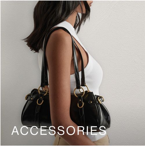 Woman posing in front of a white wall wearing a white top, standing in front of a white wall with text overlay which states "Accessories"