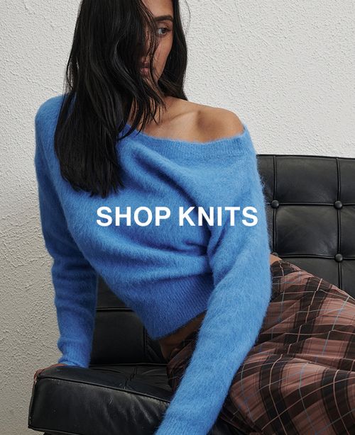 Woman in a blue knit in front of a white wall with text that reads "20% off all Knits"