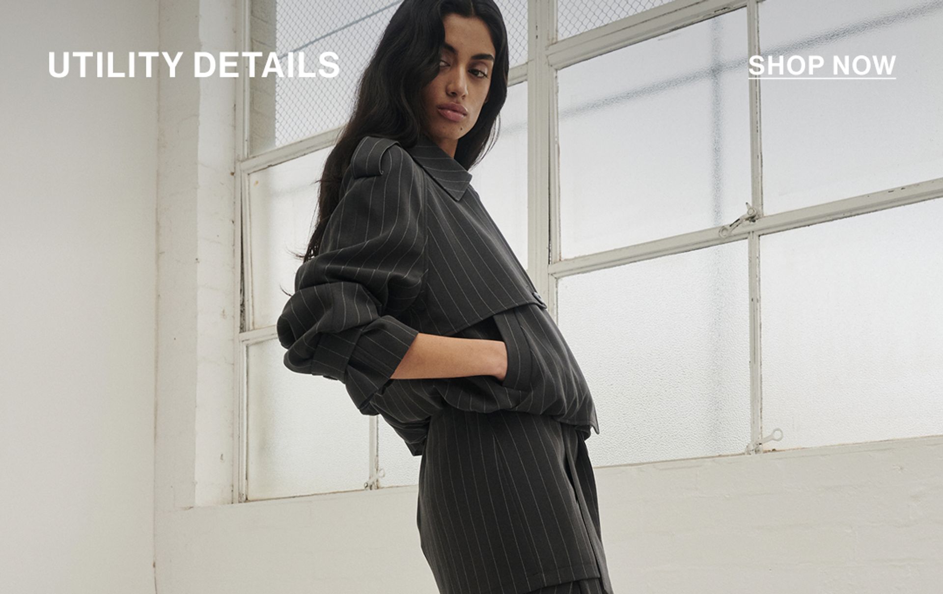 Model in a leather jacket standing in front of a white wall with text overlay which states "20% OFF DLUXE BASICS"
