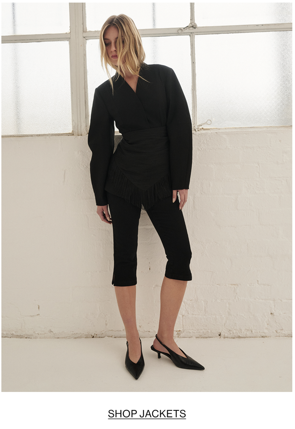 Woman posing is black barrel blazer with text that states shop jackets