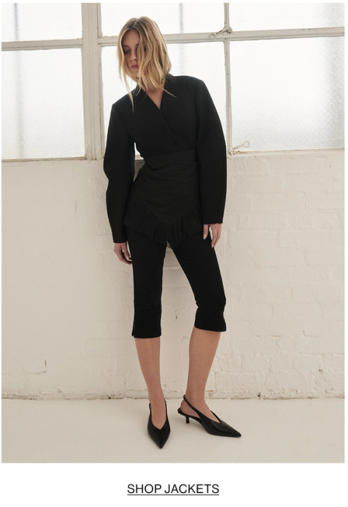 Woman posing is black barrel blazer with text that states shop jackets