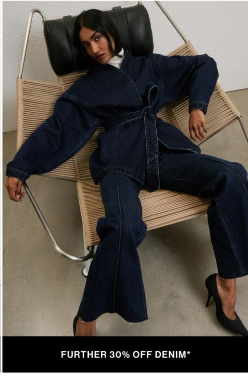 Woman sitting in a modern chair wearing double denim with text overlay which states "further 20% off denim"
