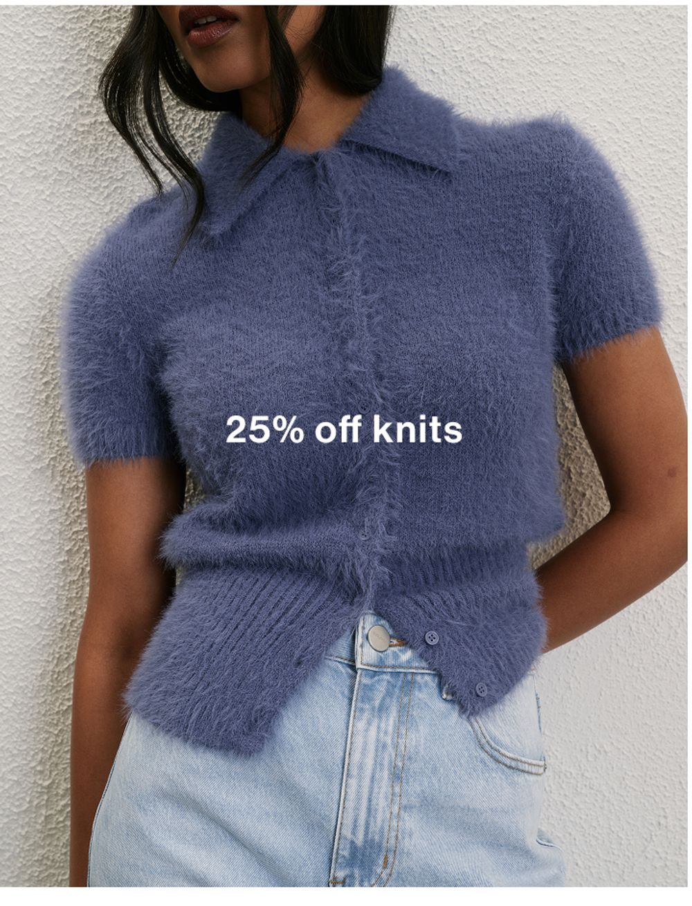 Woman standing in front of a white wall with text that reads "25% off jackets"