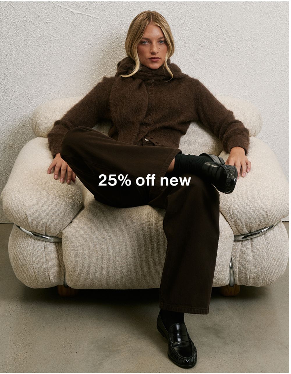Woman sitting in a chair, wearing a brown suit and sunglasses with text that reads "25% off new"