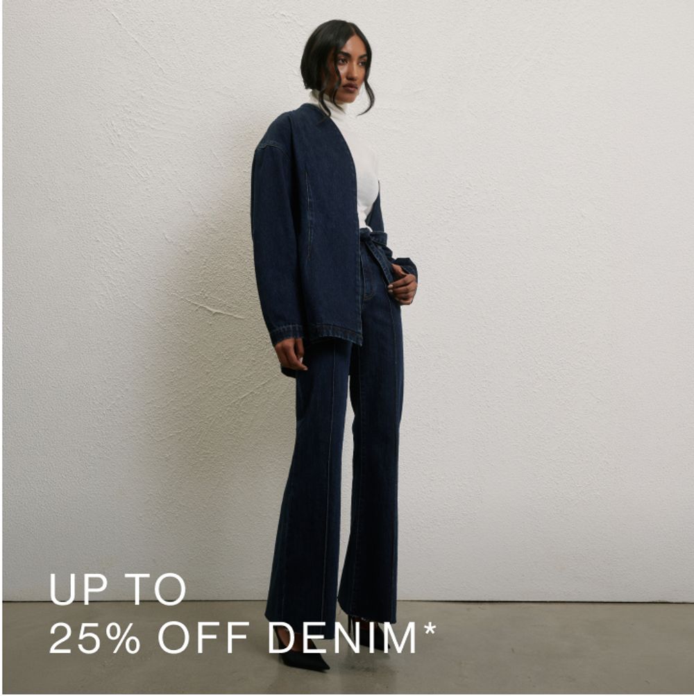 Woman wearing a black turtle neck top standing in front of a white wall with text that states 25% off tops