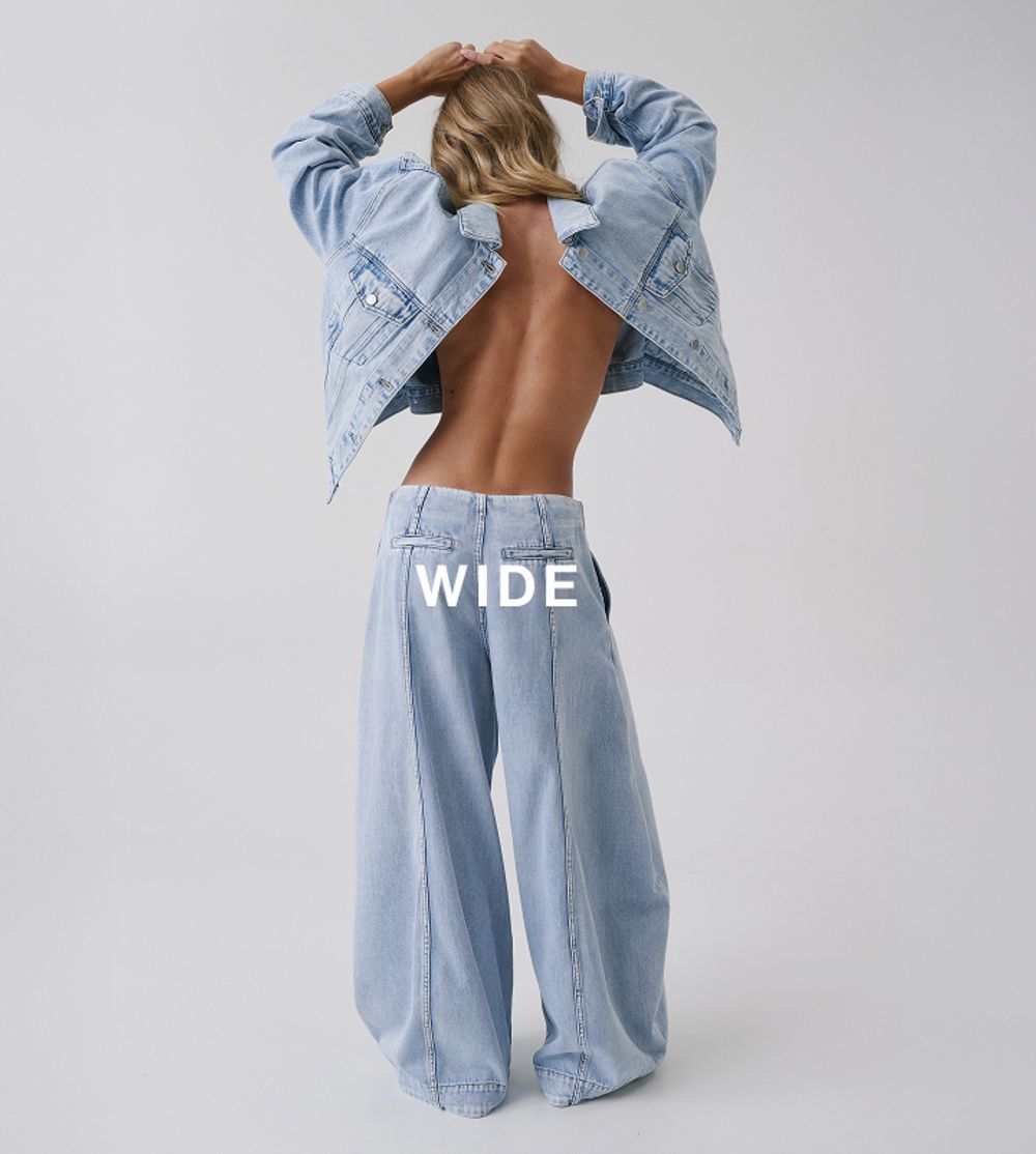 Model standing with her back toward the wall, wearing a matching denim set which has text overlay wide