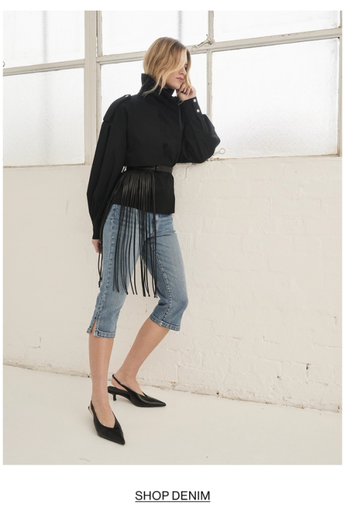 Woman posing in black knit with text that states shop denim