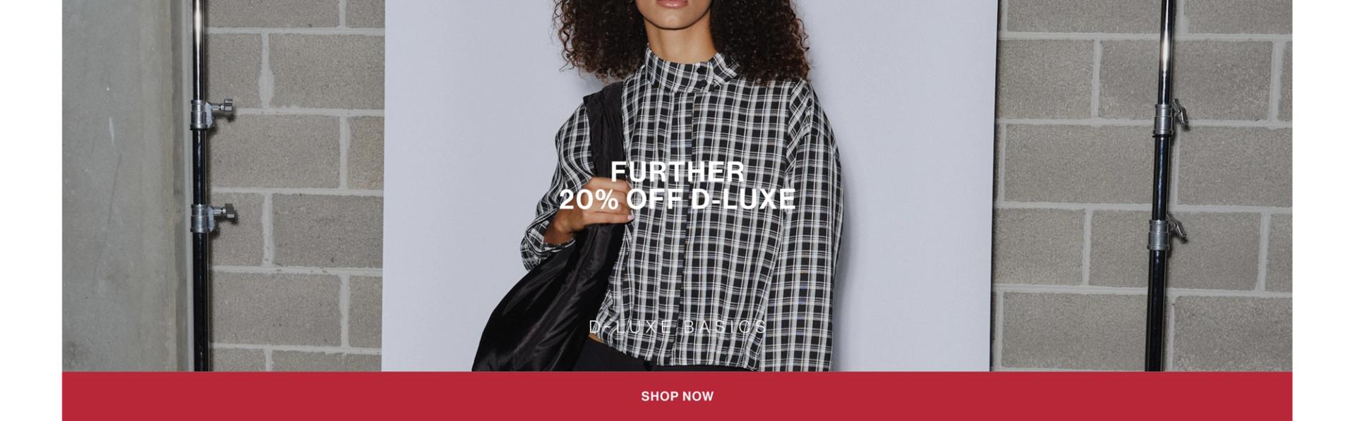 Model in a leather jacket standing in front of a white wall with text overlay which states "20% OFF DLUXE BASICS"