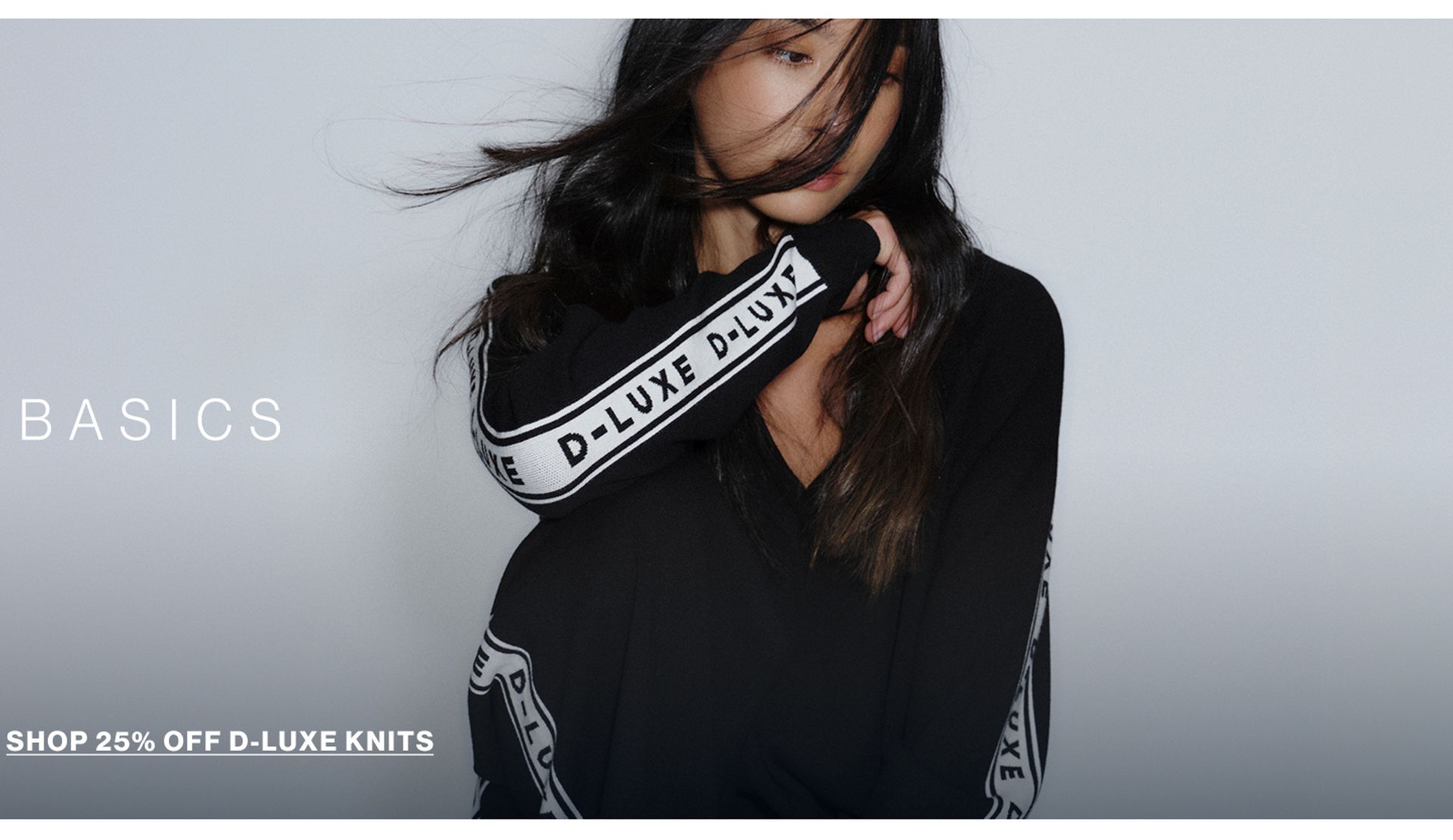 Model in a leather jacket standing in front of a white wall with text overlay which states "20% OFF DLUXE BASICS"