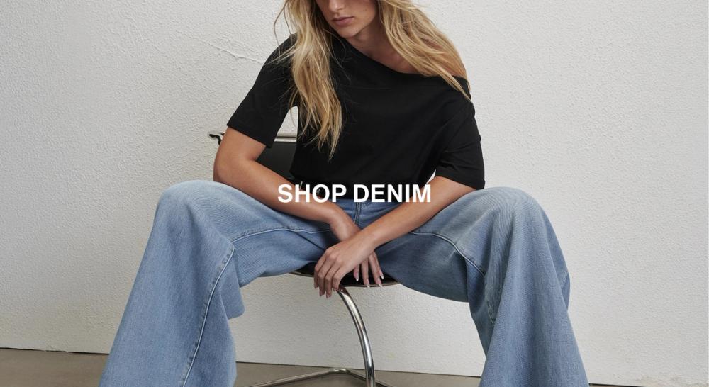 Model wearing a black off shoulder top with denim jeans. Text reads SHOP DENIM
