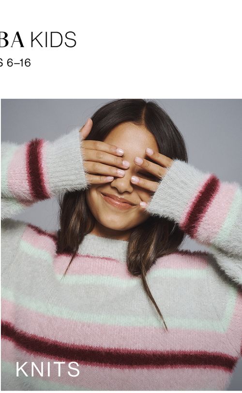 Young girl wearing a pink stripe knit cardigan. SHOP TEEN KNITWEAR.